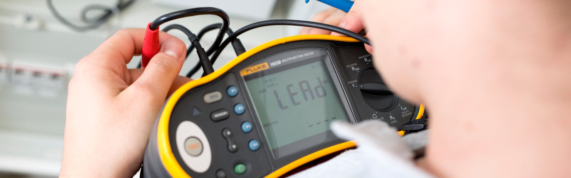 Elektrofachkraft prüft einen Schaltschrank mit Messgerät