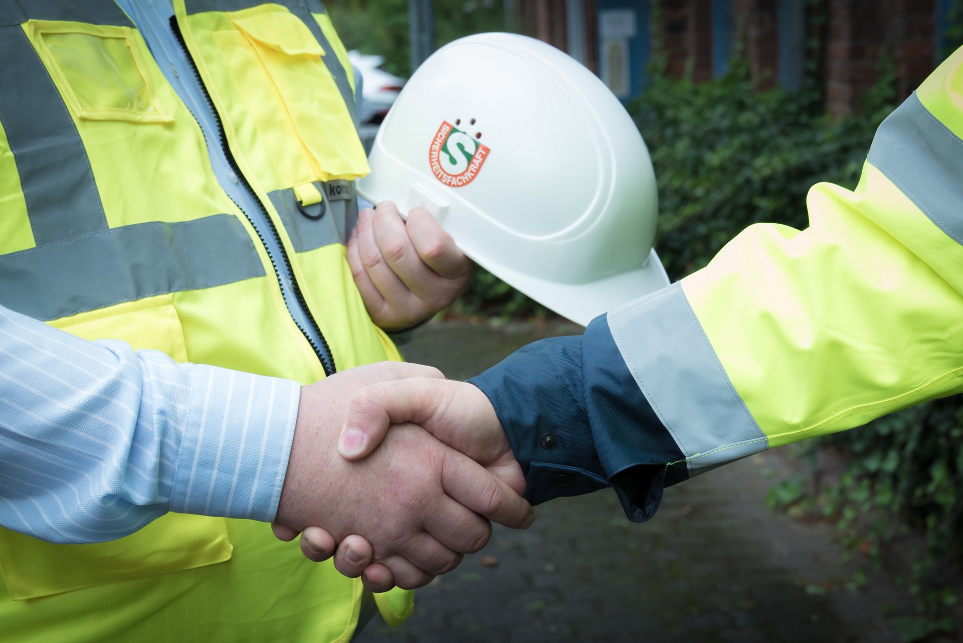 Handschlag bei der Arbeitsschutzbetreuung Handschlag zwischen einem Kunden und einer Fachkraft für Arbeitssicherheit mit Sicherheitshelm